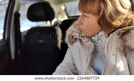 Woman sitting in the car in road trip. Blonde senior Woman driving transport. Lady travelling in cold time