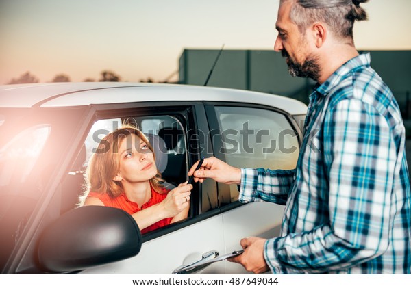 Woman\
sitting in the car and signing car rental\
agreement