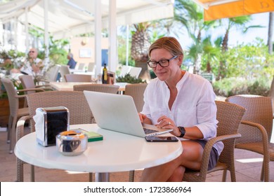 Woman sitting in a coffee bar working on her laptop. She is looking down on the screen.