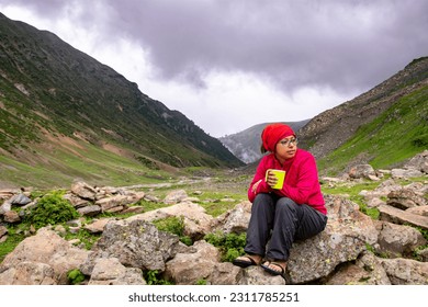 Woman sitting with coffee cup in front of the beautiful valley of Kashmir, India. - Shutterstock ID 2311785251