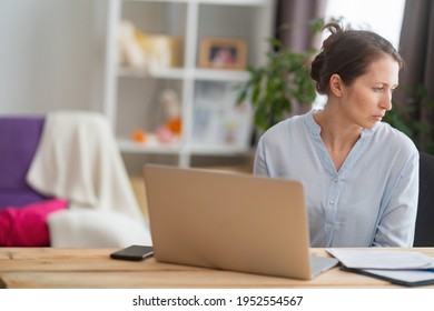 Woman Sitting At A Desk At Home Working With A Computer Laptop Is Tired And Bored At Office Work. Unmotivated Lazy Brown-haired Woman Feels Sleepy At A Boring Job And Lack Of Sleep