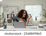 A woman is sitting at a desk with a laptop and a stack of papers. She is holding a piece of paper and she is angry