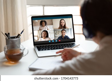 Woman Sitting At Desk Noting Writing Information Studying At Home With Multiracial Students Diverse Ladies Makes Video Call Using Video Conference Application, View Over Girl Shoulder To Laptop Screen