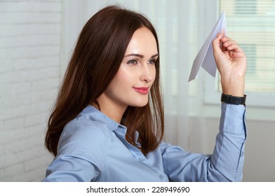 Woman Sitting At A Desk In An Office And Throwing A Paper Plane