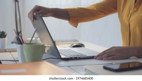 Woman Sitting At Desk And Opening The Laptop Lid