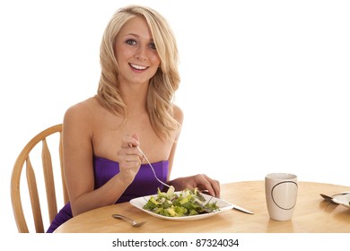 A Woman Sitting Down In Her Fancy Dress Eating Her Salad With A Smile On Her Face.