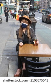Woman sitting down at an outdoor table in the city