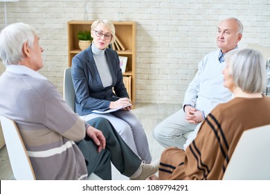 Woman Sitting With Elderly People In Circle Having Consultation While Working In Assisted Living Home. 