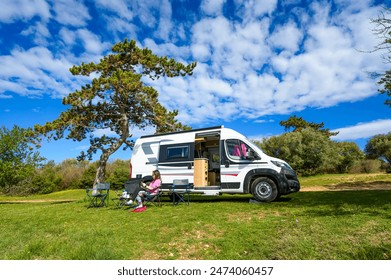 Woman sitting in front of campervan or motorhome parked on the beach. Tourist woman enjoying and relaxing on the beach with RV camper van on family vacation. - Powered by Shutterstock