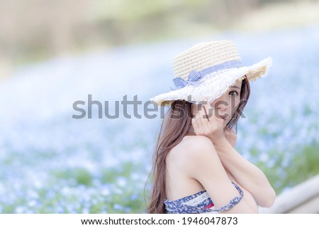 Up of a woman sitting in a hat in the nemophila field