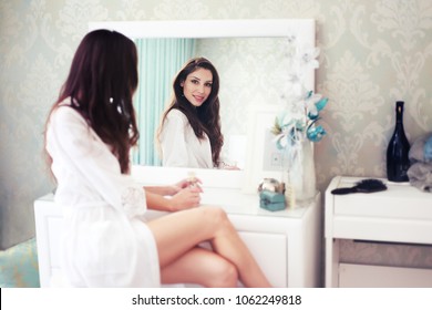 Woman Sitting In Her Bedroom And Looking Into A Boudoir Mirror