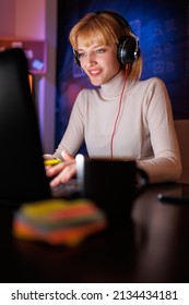 Woman Sitting At Her Desk In Home Office Working Late At Night Using Laptop Computer; Female Software Developer Working Overtime Remotely From Home