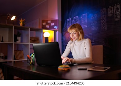 Woman sitting at her desk in home office working late at night using laptop computer; female web designer working overtime remotely from home - Shutterstock ID 2134434205