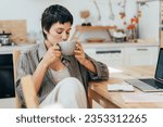 Woman sitting in the kitchen drinking coffee.