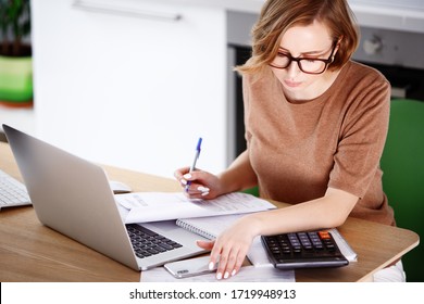 Woman sitting at laptop computer, making notes, calculating expenses, planning family budget, debts and credits, mortgage and rent. Remote working of employee at home, or start up of business woman