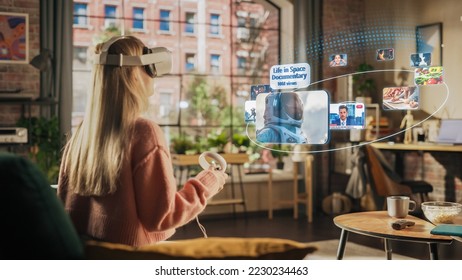 Woman Sitting in Loft Living Room at Home, Using Virtual Reality Headset with Controllers to Check Social Media Streaming App, Browsing Social Network Feed, Liking Posts, Watching Videos - Shutterstock ID 2230234463