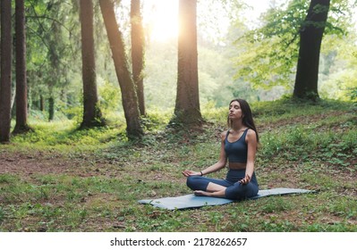 Woman sitting in the lotus position outdoors in nature, meditation and yoga concept - Powered by Shutterstock