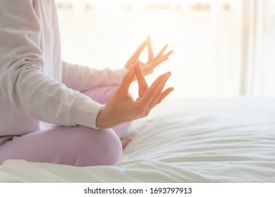 A woman sitting meditation on bed in the morning
