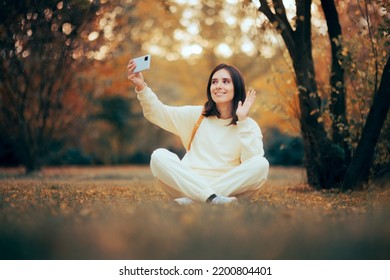 

Woman Sitting In Nature Making A Video Call. Cheerful Travel Girl Making A Video With Her Phone Camera Outdoors 
