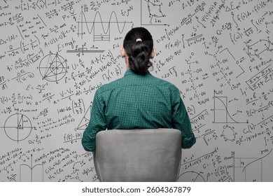 A woman is sitting near a wall with a drawing of mathematical equations, graphs amd diagrams. Idea generating and thinking concept