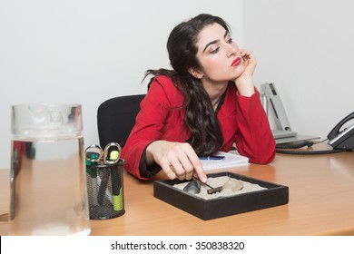 Woman Sitting In The Office Bored Playing With A Zen Garden 