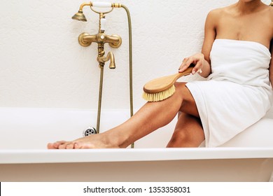 Woman Sitting On A Bath While Dry Brushing Her Legs