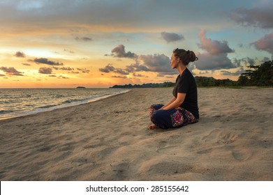 Woman sitting on beach sand and relaxing at sunset time - Shutterstock ID 285155642