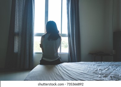woman sitting on bed in room with light from window abuse concept