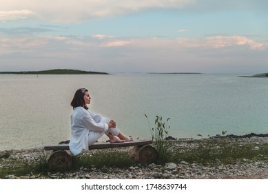 woman sitting on bench looking on sunset over the sea