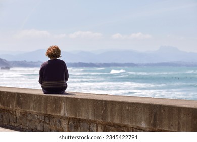 woman sitting on a bench looking at the sea - Powered by Shutterstock