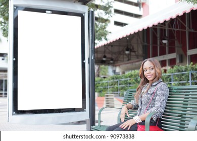 Woman sitting on a bus stop bench with a blank sign