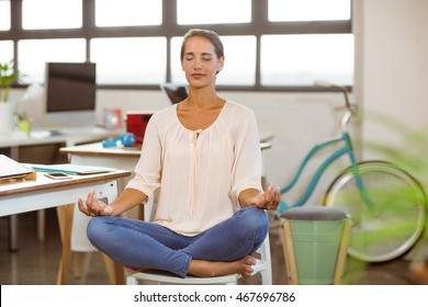 Woman Sitting On Chair And Performing Yoga In Office