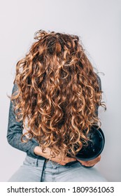 Woman Sitting On Chair Styling Her Curly Hair With Hairdryer