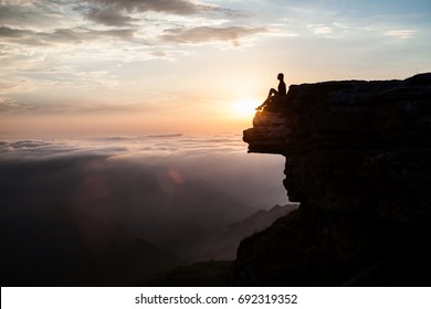 Woman sitting on the cliff and enjoying sunset - Powered by Shutterstock