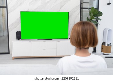 Woman Sitting On The Couch And Watching Tv. Green Screen Concept	