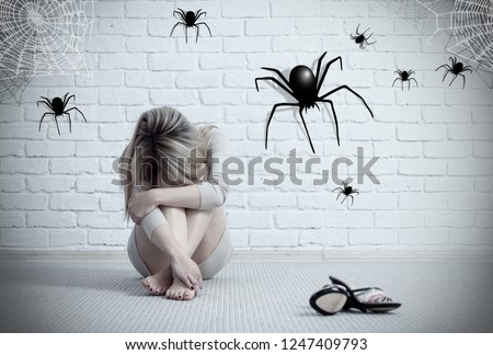 Woman sitting on the floor and looking on imaginary spider. Fear of spiders. Arachnophobia concept.