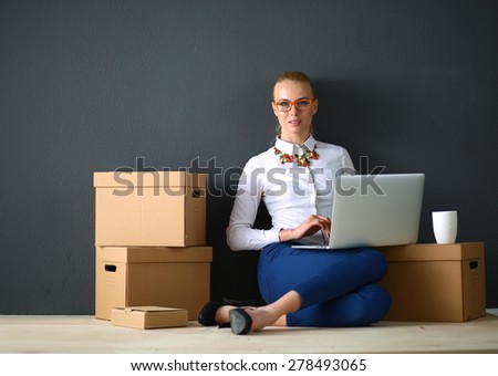Woman sitting on the floor near a boxes  with laptop 