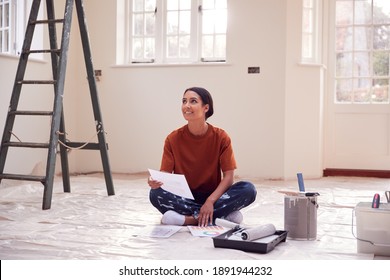 Woman Sitting On Floor With Paint Chart Ready To Decorate New Home