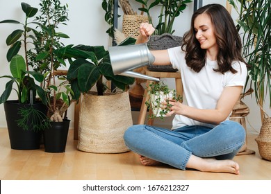 A Woman Sitting On The Floor Pours Water Into A Flower Pot, She Cares For House Plants