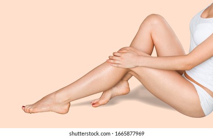 Woman sitting on the floor and touching her leg by hands