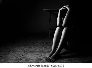 woman sitting on ground with arm around lower head, sexual violence , sexual abuse, human trafficking concept with shadow edge in white tone