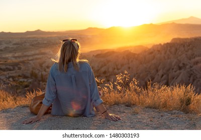 Woman sitting on the ground watching sunset over Cappadocia valley.  - Powered by Shutterstock