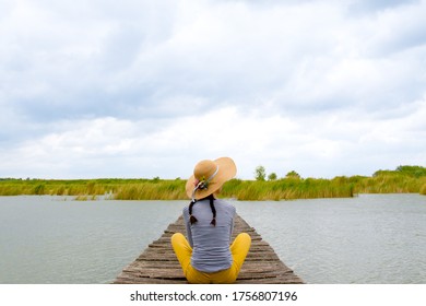Woman sitting on the lake next to water and enjoining in look in distance. Enjoy in nature. Relaxation. Vacation on lake - Shutterstock ID 1756807196