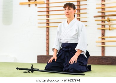 Woman sitting on mats while Aikido training in martial arts school