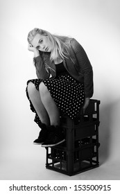 Woman Sitting On Milk Crates Shot In The Studio On White Background