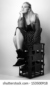 Woman Sitting On Milk Crates Shot In The Studio On White Background