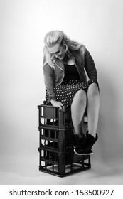 Woman Sitting On Milk Crates Shot In The Studio On White Background