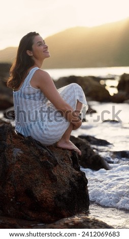 Woman sitting on ocean beach in tropical paradise island with turquoise water waves, white sand in sunny weather. Girl admire seascape. Beach resting, travel, tourism.
