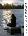 Woman sitting on ottoman at lakefront, Kenora, Lake of the Woods, Ontario, Canada