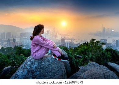 Woman Sitting On The Rock And Looking To Hong Kong At Sunset.